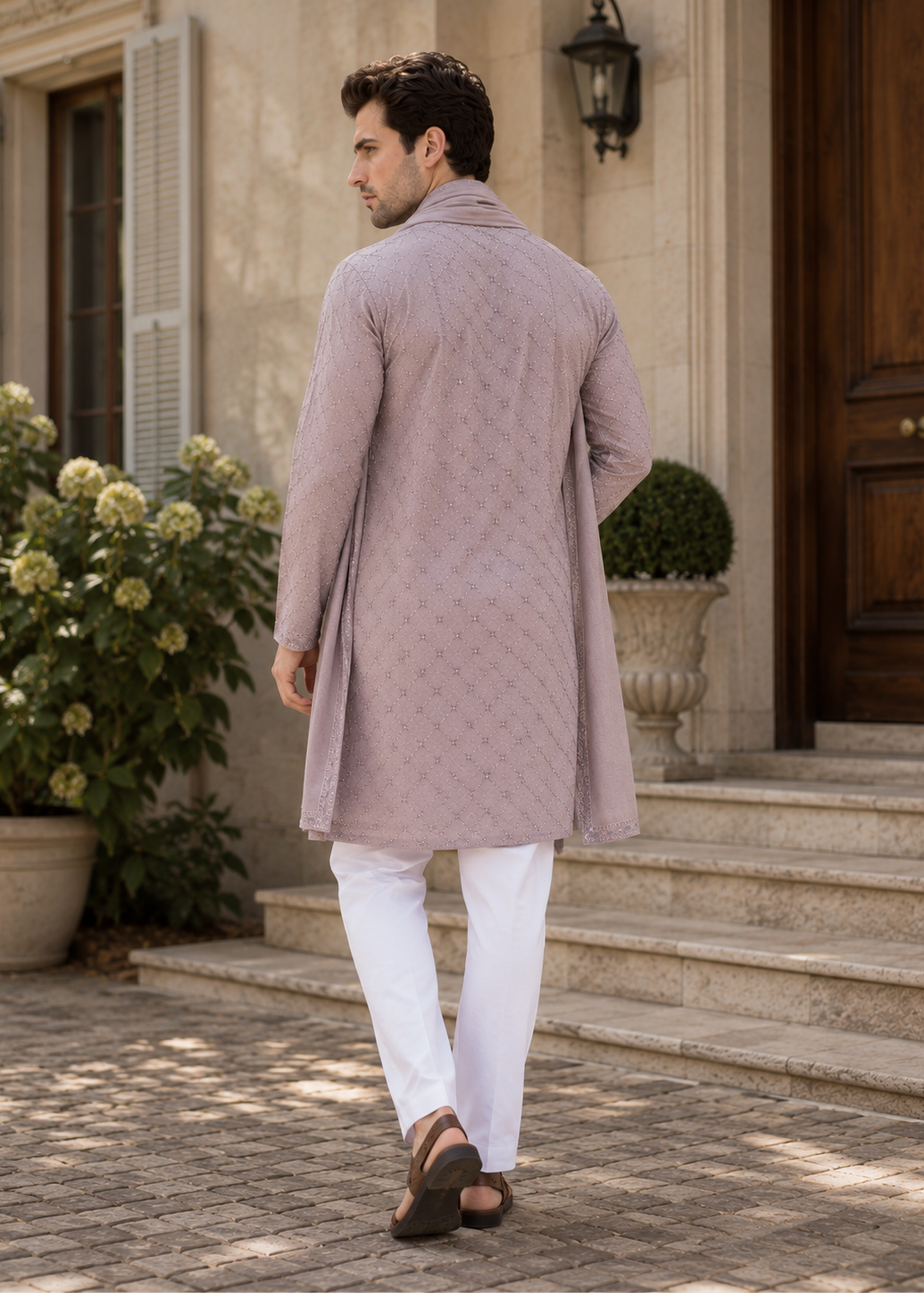 Man wearing a mauve kurta with white pants walking outside a building.
